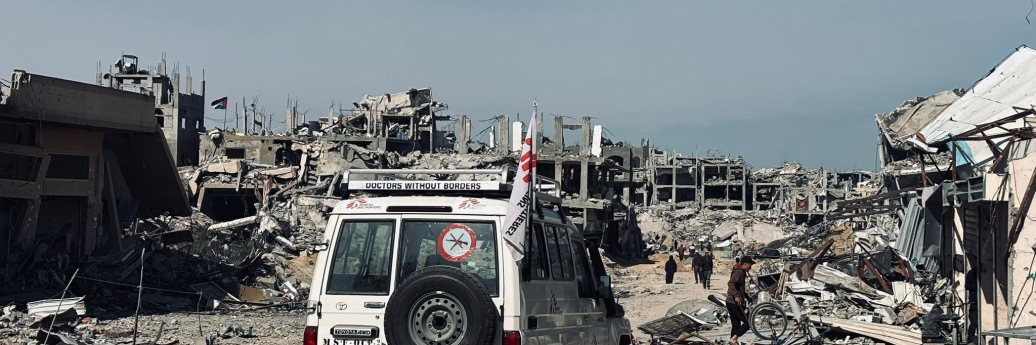 An MSF vehicle passes in front of ruined buildings in Jabalia.