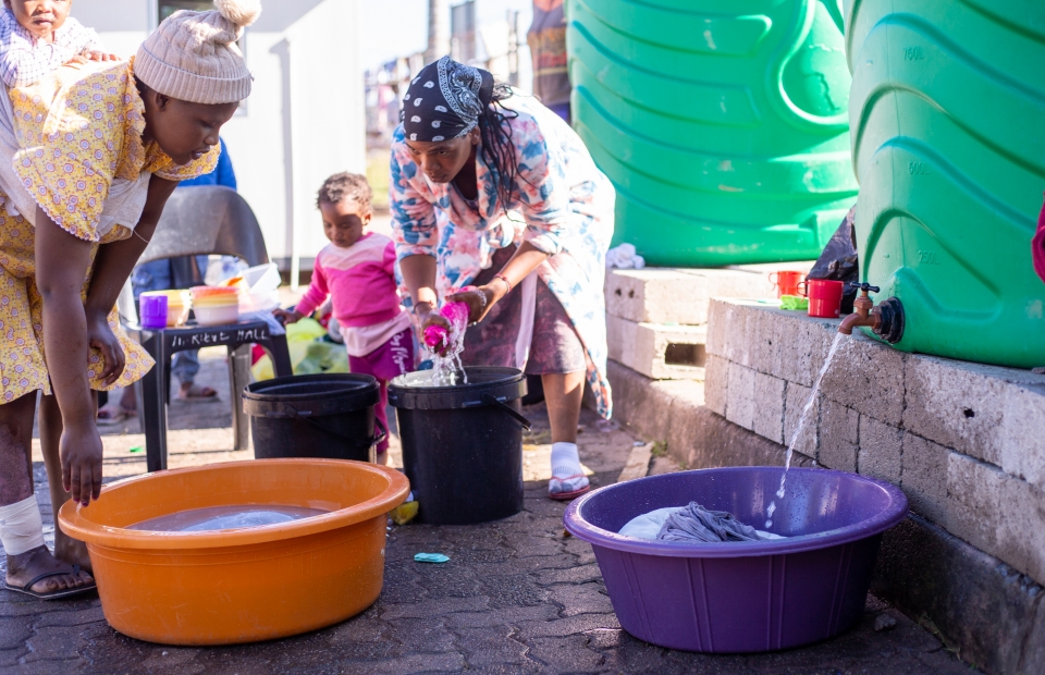 vrouwen in Zuid-Afrika nemen water uit een ton